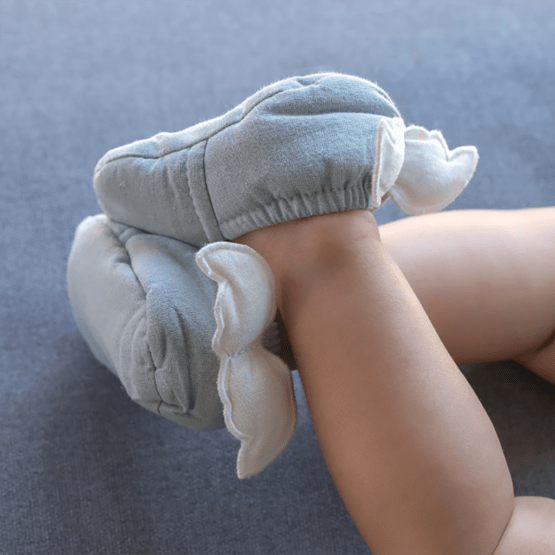 Une paire de chaussons bébé vert de gris avec des ailes d'anges BB&Co, portée