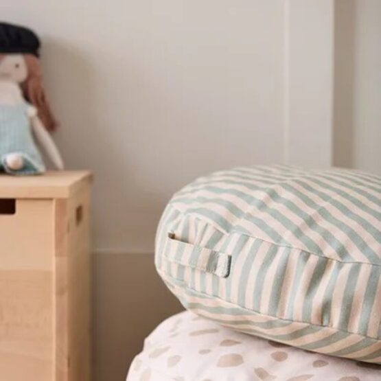 Coussin de sol rayé dans une chambre d'enfant, avec une poupée en arrière plan.